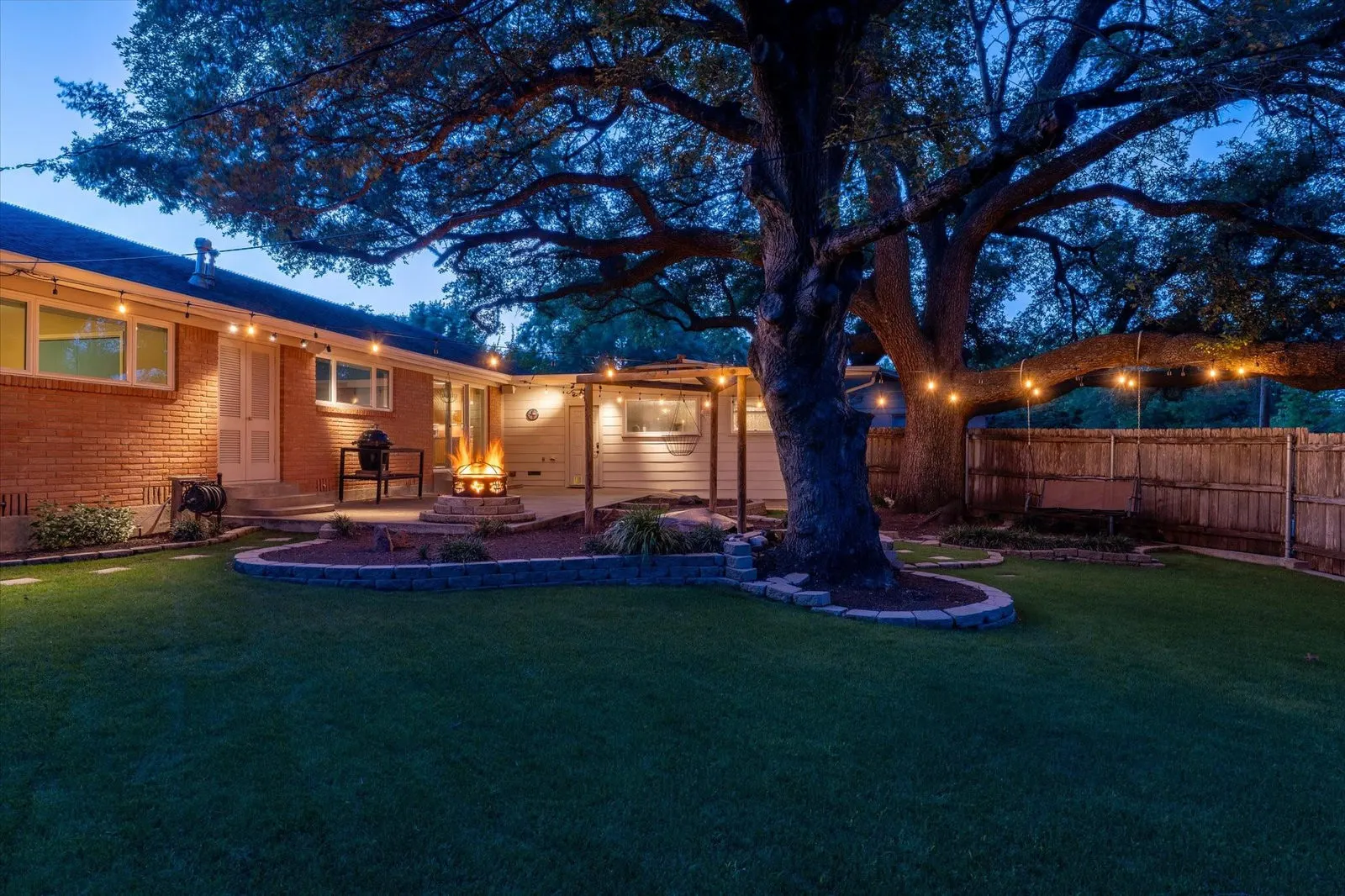 Eye-level view of a spacious backyard with a large live oak tree and a water feature