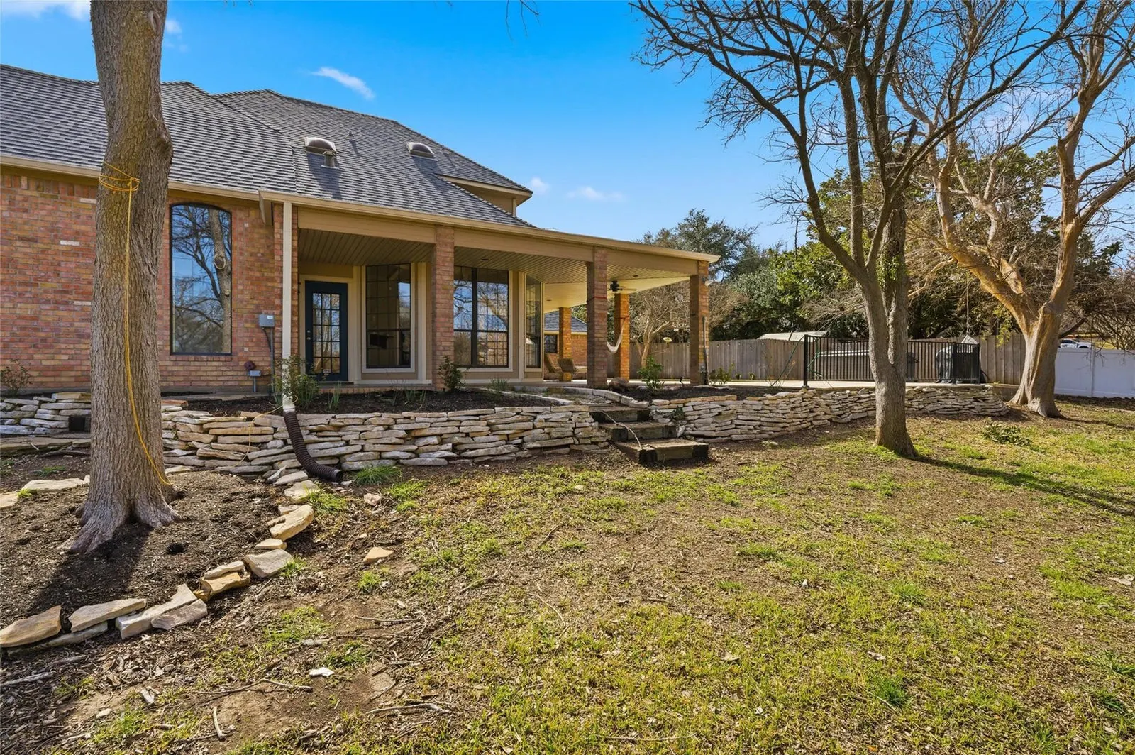 Eye-level view of the covered patio and pool area surrounded by mature trees at 804 Wooded Crest