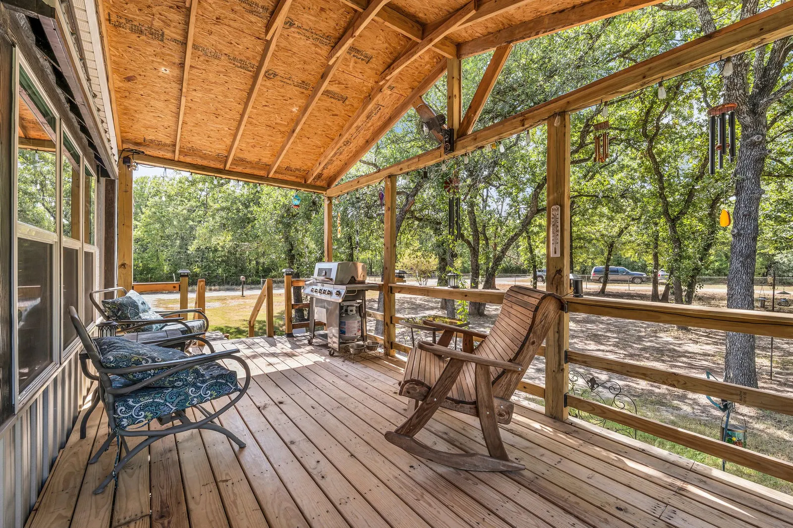 Wide-angle view of a covered front porch facing a wooded country yard.